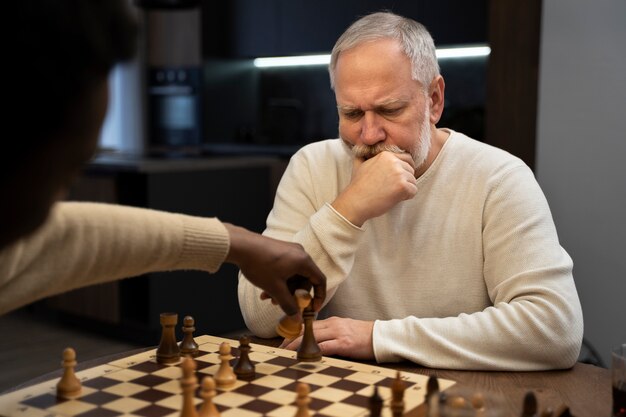 Junge und alte Männer der Seitenansicht, die Schach spielen