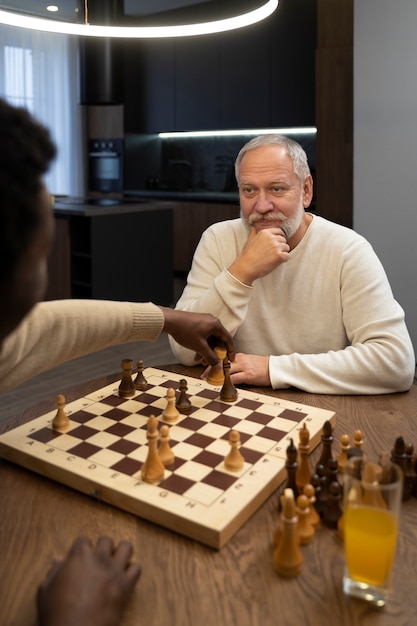 Junge und alte Männer, die Schachseitenansicht spielen