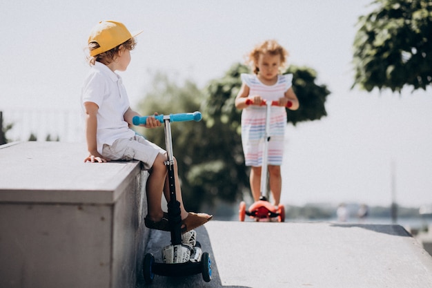 Junge und ein Mädchen, die Roller zusammen im Park fahren