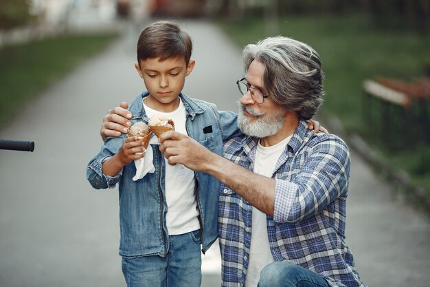 Junge und Großvater gehen im Park spazieren. Alter Mann, der mit Enkel spielt. Familie mit Eis.