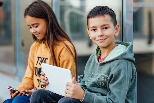 Junge und Mädchen benutzen einen digitalen Laptop beim Gehen auf der Straße und haben Wochenendzeit.