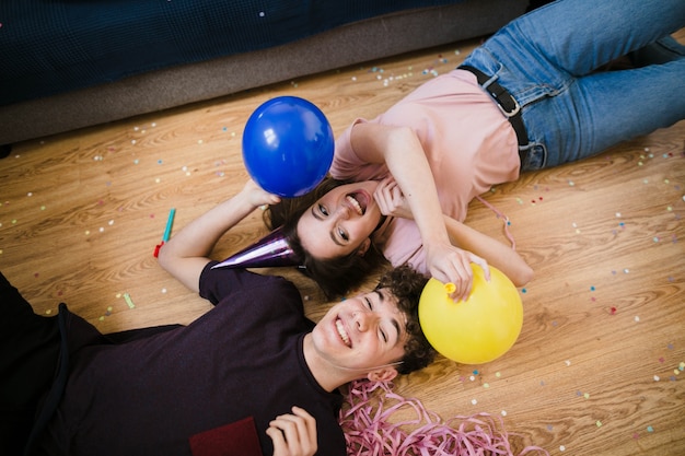 Junge und Mädchen, die auf den Boden mit Ballonen legen