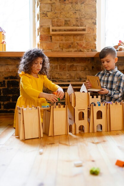 Junge und Mädchen, die drinnen mit Öko-Spielzeug spielen