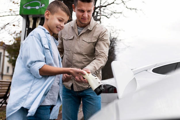 Kostenloses Foto junge und papa in der nähe eines elektroautos