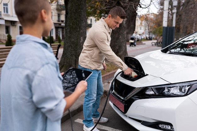 Junge und Papa in der Nähe eines Elektroautos