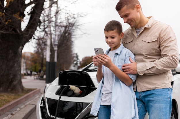 Kostenloses Foto junge und papa in der nähe eines elektroautos