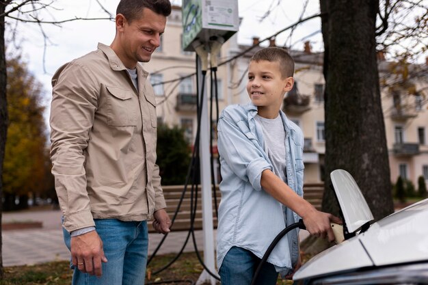Junge und Papa in der Nähe eines Elektroautos