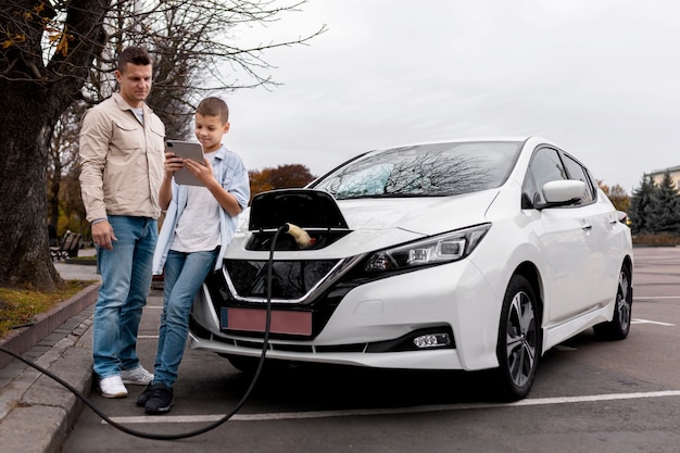 Junge und Papa in der Nähe eines Elektroautos