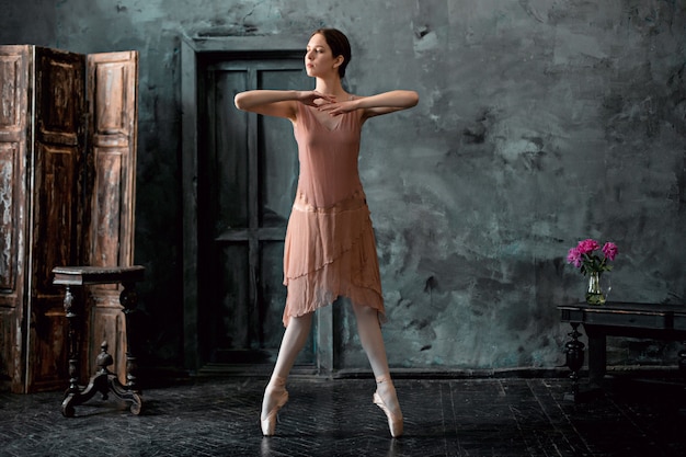 Junge und unglaublich schöne Ballerina posiert und tanzt in einem schwarzen Studio