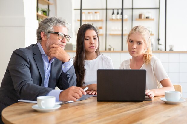 Junge Unternehmer, die dem reifen Investor eine Präsentation zeigen