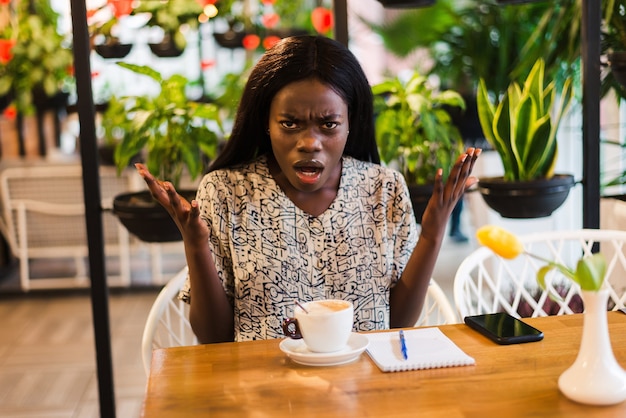 Junge verwirrte afrikanische Frau schockiert im Kaffeehaus
