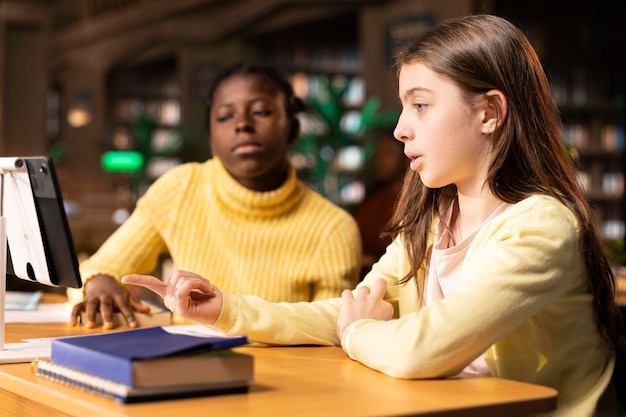 Junge, vielfältige Studenten besuchen einen Online-Kurs über einen Videogespräch in der Bibliothek