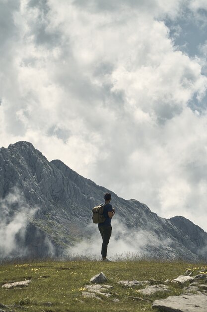 Junge Wanderer mit einem Rucksack umgeben von Bergen bei bewölktem Himmel in Kantabrien, Spanien