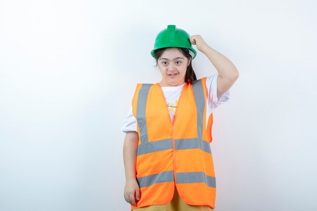 Junge weibliche Bauarbeiterin im Helm, der über weißer Wand steht