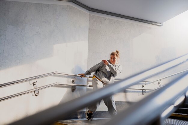 Junge weibliche Darstellerin tanzt in einem verlassenen Gebäude auf Treppen