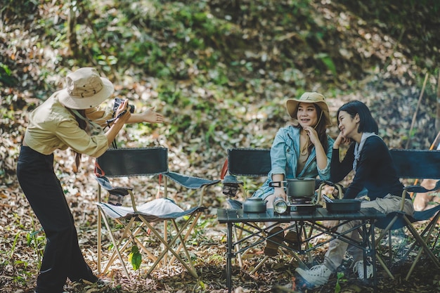 Kostenloses Foto junge weibliche fotografen genießen es, ihre freunde zu fotografieren, sie benutzen digitalkameras und schöne mädchen posieren im campingzelt im naturwald-kopienraum