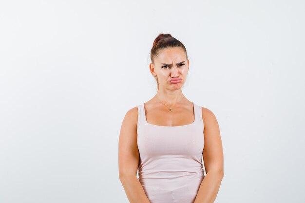 Junge weibliche geschwungene Lippen, stirnrunzelndes Gesicht im Unterhemd und unzufrieden aussehend, Vorderansicht.