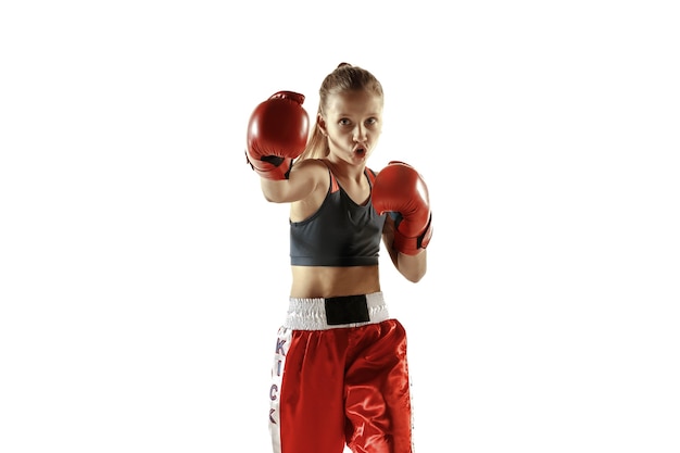 Junge weibliche Kickboxkämpferausbildung lokalisiert auf weißer Wand. Kaukasisches blondes Mädchen in der roten Sportbekleidung, die in den Kampfkünsten praktiziert. Konzept von Sport, gesundem Lebensstil, Bewegung, Aktion, Jugend.