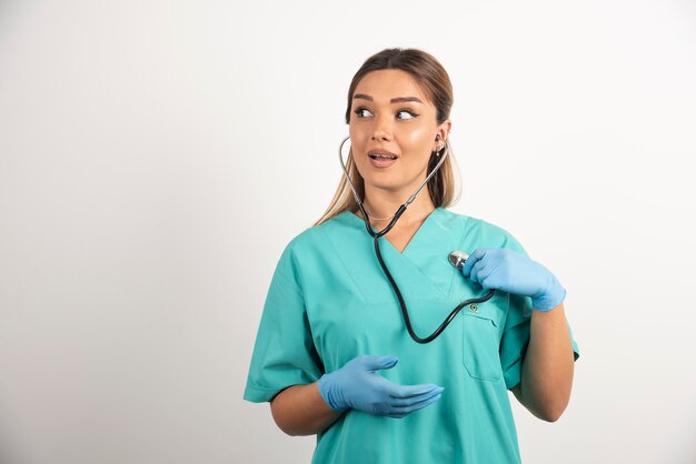 Junge weibliche Krankenschwester, die mit Stethoskop aufwirft.