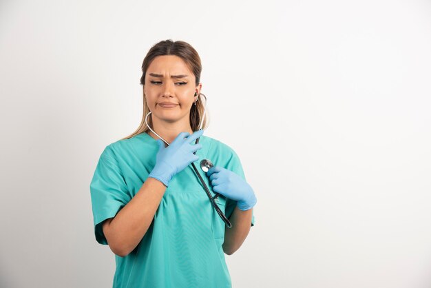 Junge weibliche Krankenschwester, die mit Stethoskop aufwirft.