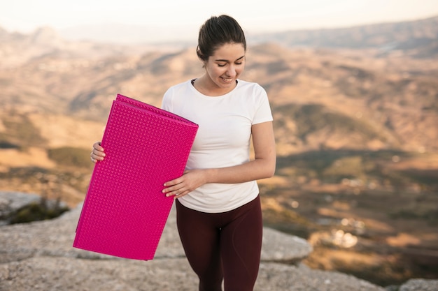 Junge weibliche tragende Yogamatte des hohen Winkels