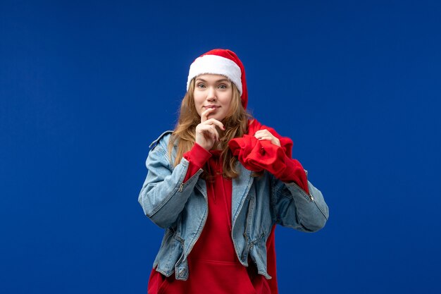 Junge weibliche Tragetasche der Vorderansicht voller Geschenke auf blauen Schreibtischfarbemotionsweihnachten
