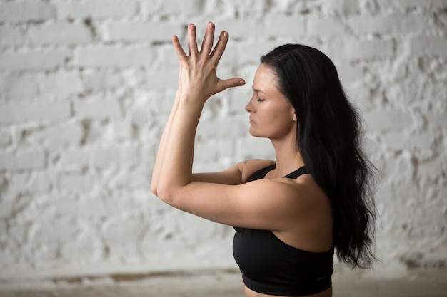 Junge Yogi attraktive Frau macht namaste, weiße Loft backgroun