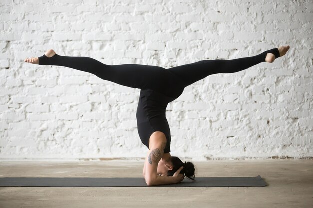 Junge Yogi attraktive Frau macht Salamba sirsasana Pose mit sp