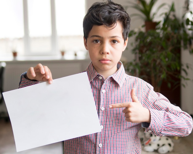 Kostenloses Foto junge zeigt auf leeres papierblatt