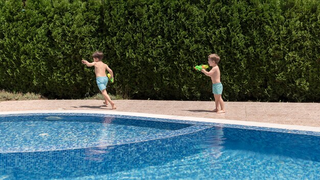 Jungen am Pool spielen mit Wasserpistole