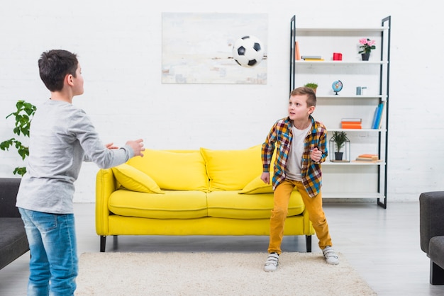 Jungen, die Fußball im Wohnzimmer spielen