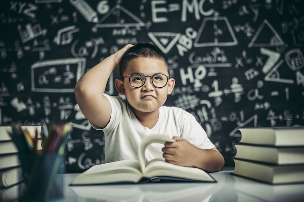 Jungen mit Brille schreiben Bücher und denken im Klassenzimmer