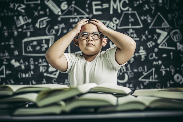 Jungen mit Brille schreiben Bücher und denken im Klassenzimmer