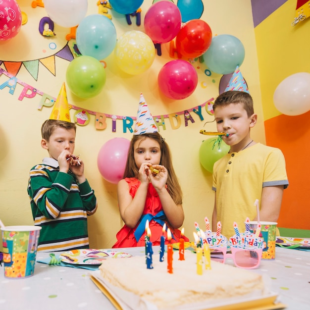 Jungen und Mädchen, die Partyhörner durchbrennen