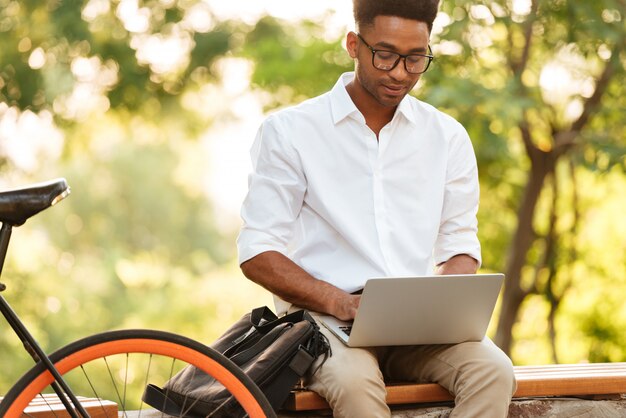 Junger afrikanischer schöner Mann, der Laptop-Computer verwendet.