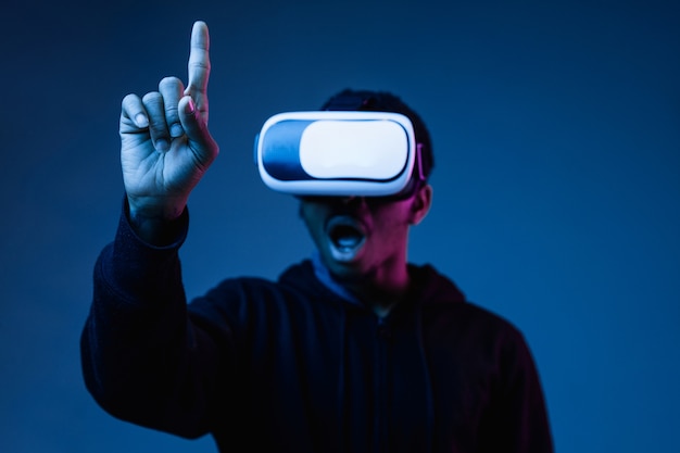 Junger Afroamerikaner in VR-Brille im Neonlicht auf Blau