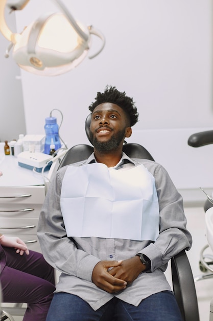 Junger Afroamerikaner. Mann besucht Zahnarztpraxis zur Vorbeugung der Mundhöhle. Mann und Familienarzt während der Kontrollzähne.