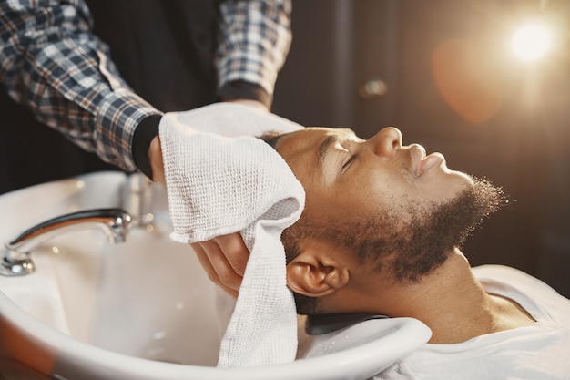 Junger afroamerikanischer Mann, der Friseursalon besucht