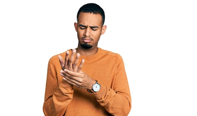 Junger afroamerikanischer Mann in lässiger Kleidung leidet unter Schmerzen an Händen und Fingern, Arthritis-Entzündung