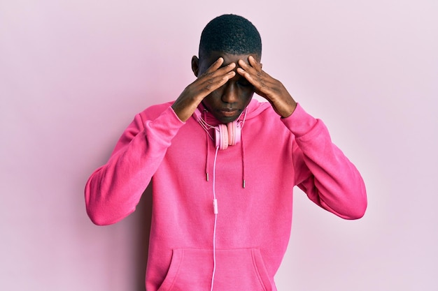 Kostenloses Foto junger afroamerikanischer mann trägt sportkleidung und benutzt kopfhörer mit der hand auf dem kopf wegen kopfschmerzen, weil er unter migräne leidet