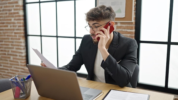 Junger arabischer Geschäftsmann spricht auf dem Smartphone und liest im Büro ein Dokument