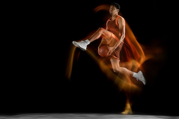 Junger arabischer muskulöser Basketballspieler in Aktion, Bewegung lokalisiert auf Schwarz