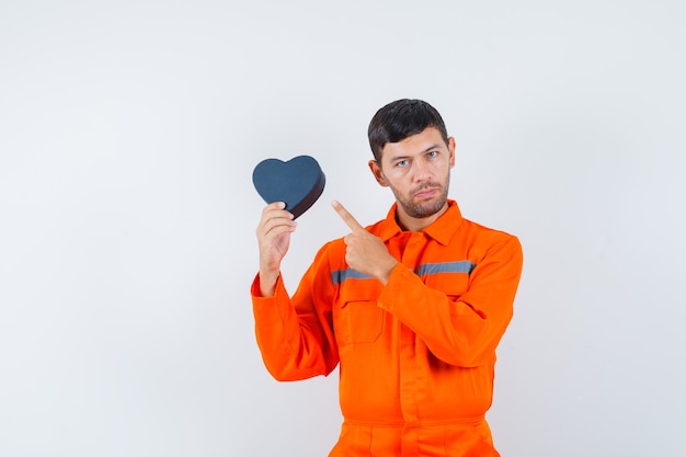 Junger Arbeiter in Uniform, die auf gegenwärtiges Kästchen zeigt.