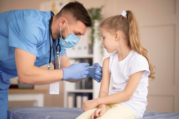 Junger Arzt, der ein kleines Mädchen impft