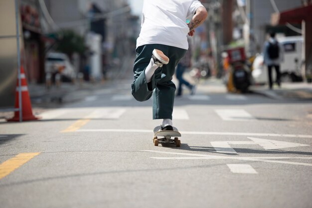 Junger asiatischer Mann, der draußen in der Stadt Skateboard fährt