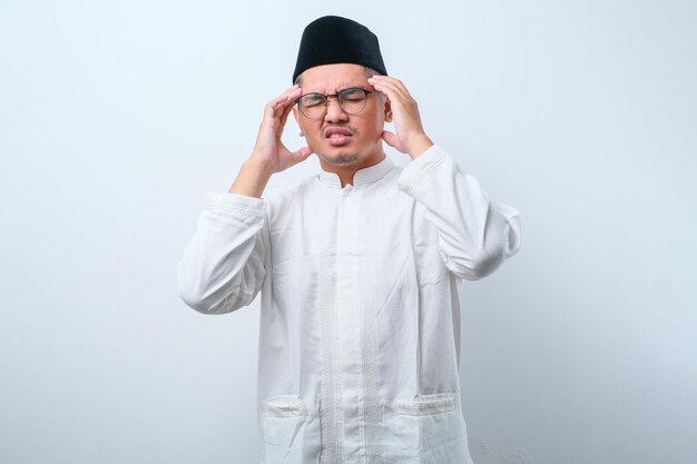 Junger asiatischer muslimischer mann, der seinen kopf hält und unter kopfschmerzen leidet, mit kopienraum isoliert auf weißem hintergrund