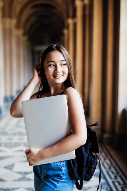 Junger asiatischer Student auf Universitätscampus mit Laptop