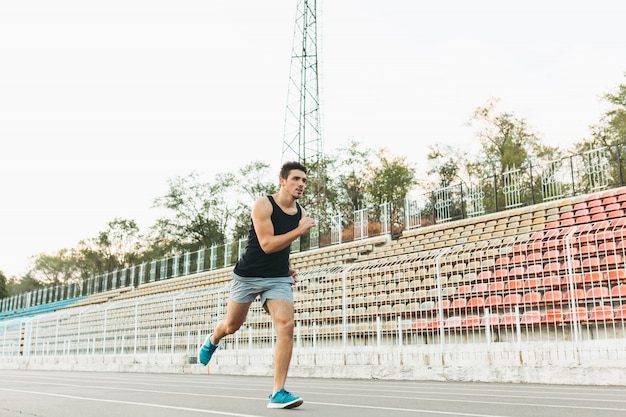 Junger athletischer Mann, der morgens auf dem Stadion läuft