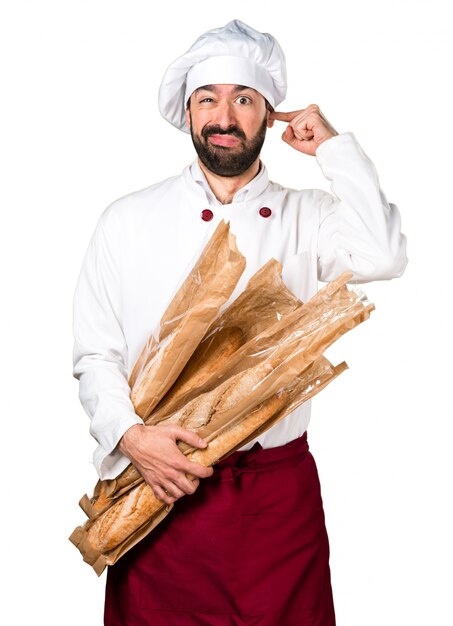 Junger Bäcker hält Brot und bedeckt seine Ohren