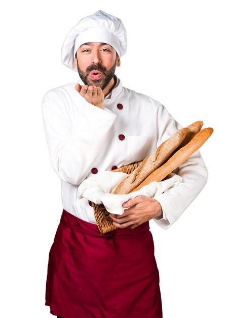 Junger Bäcker hält Brot und schickt einen Kuss